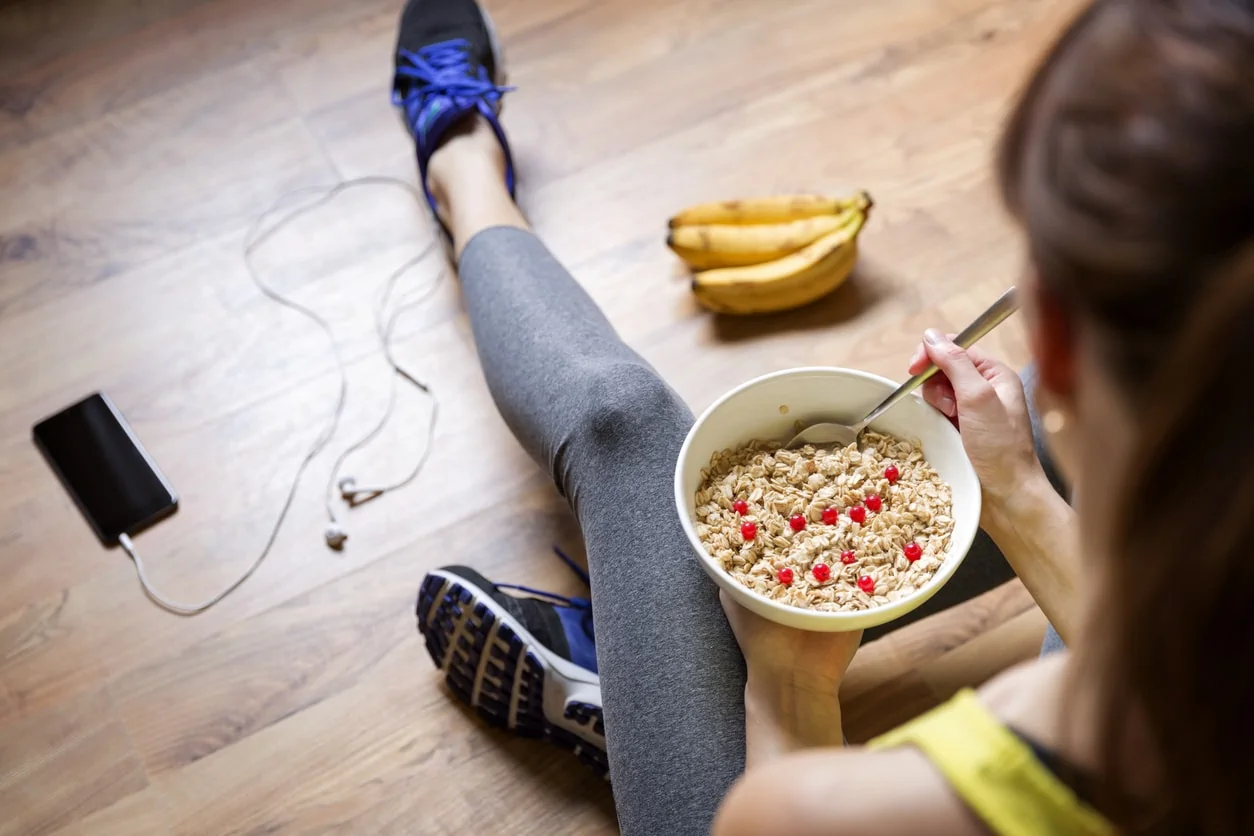 Young woman eating oatmeal with berries after a workout. Fitness and healthy lifestyle concept.