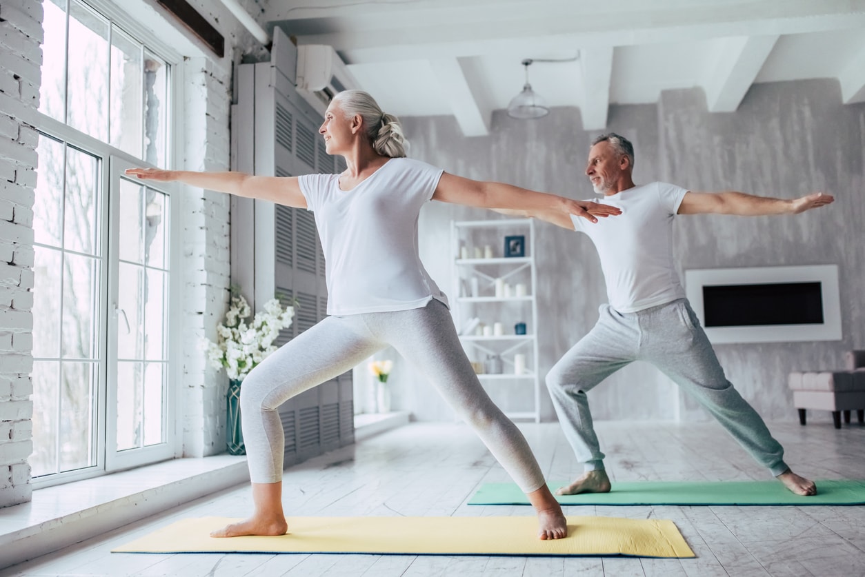 Senior couple doing yoga together at home.