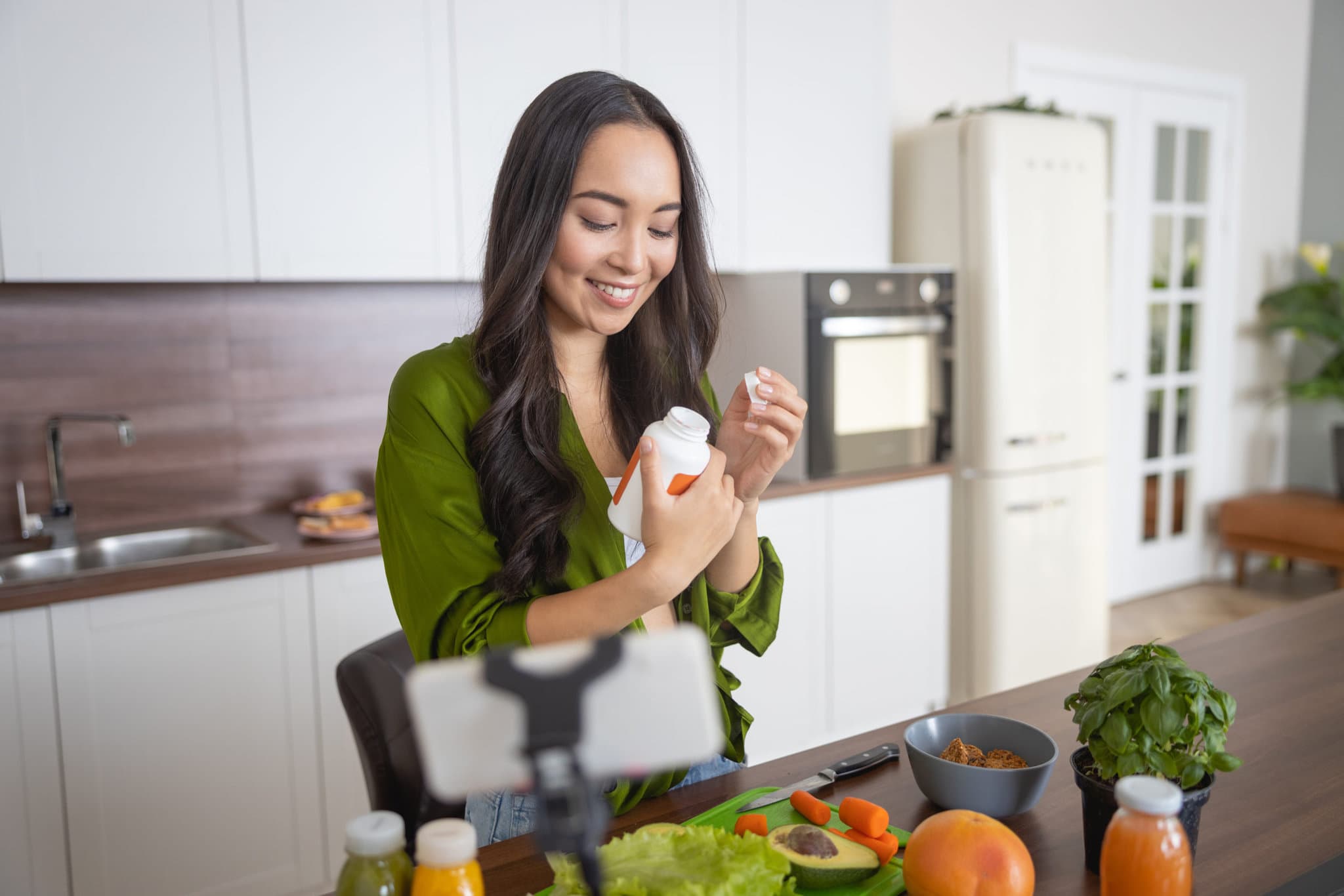 Smiling young lady looking at a bottle of supplements