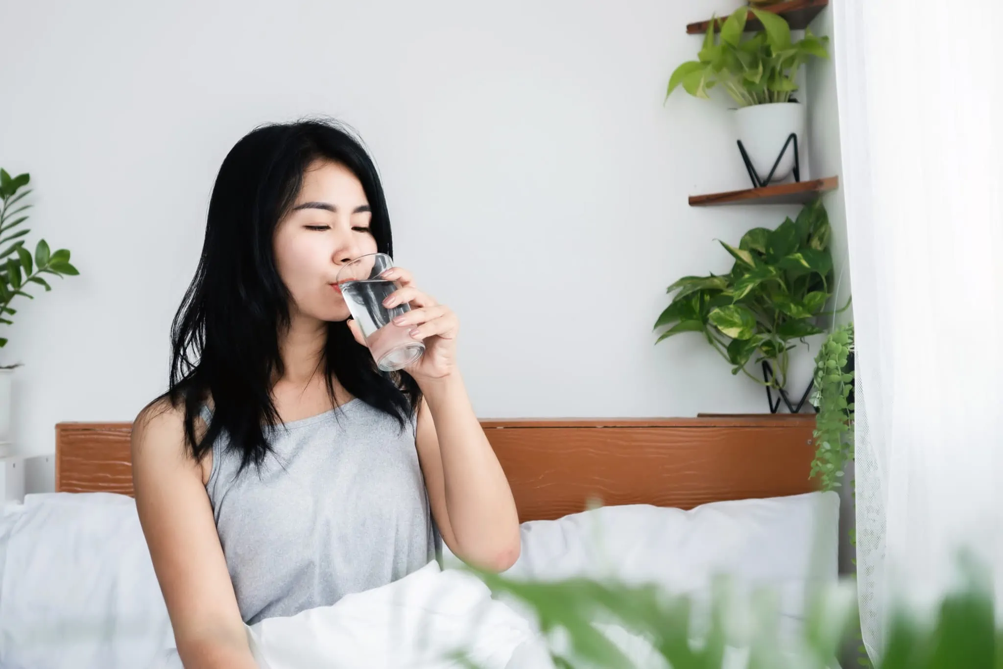 Young woman drinking a glass of water when she wakes up